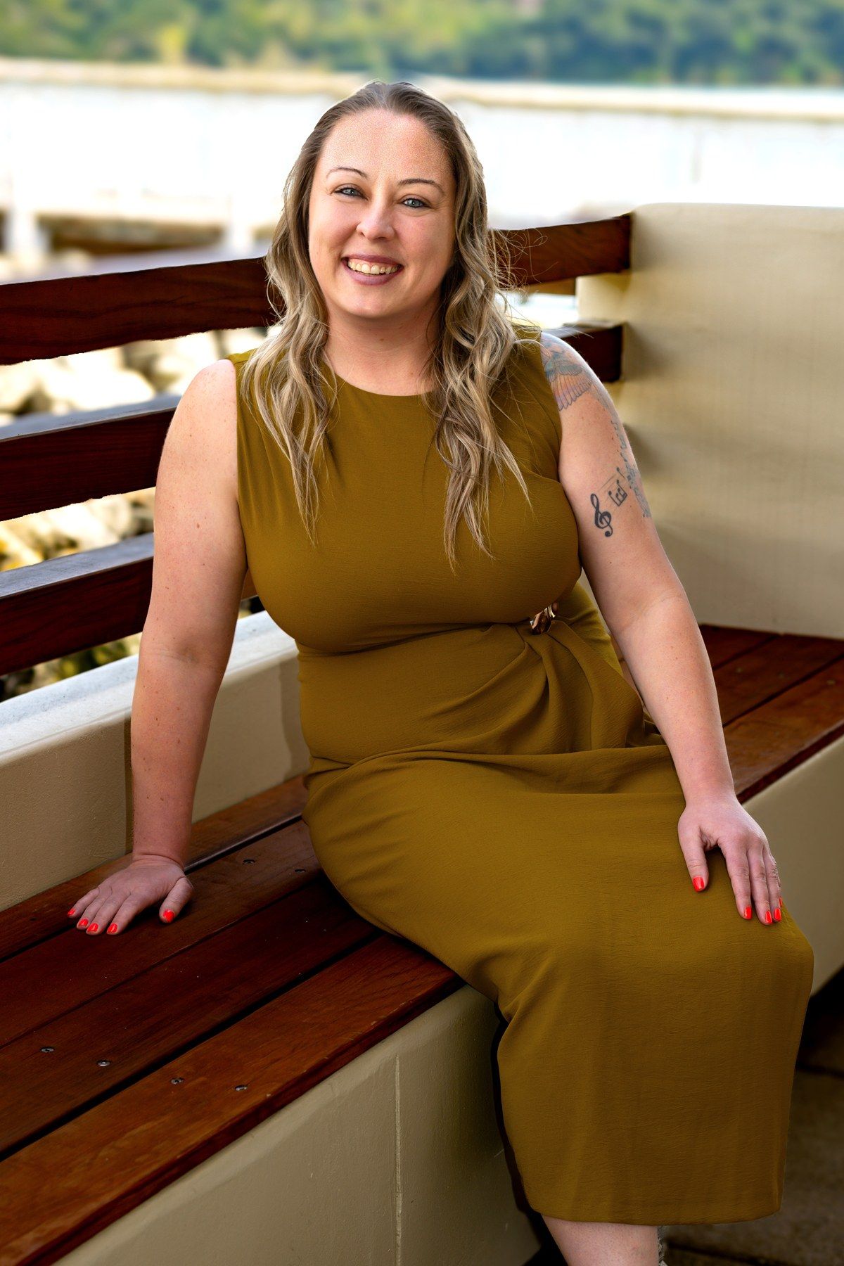 Michele seated by the water in an olive dress